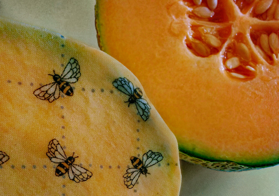 beeswax wrap with honeybee design covering a cantaloupe melon. Allows your food to breathe. reusable, sustainable eco-friendly